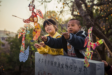 比试一下。7岁的李文龙（右）是小小皮影迷，经常和同学比一比。