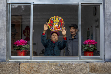 2025年1月25日，春节前夕，山东省青州市庙子镇窦家崖村王本祥（右）和高洪美在贴窗花，等孩子们回家过年。