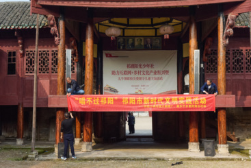?2024年11月6日拍于祁阳市九牛坝小学，活动组织者市文化馆副馆长蒋少华同工作人员在舞台前拉挂下乡活动的横幅。