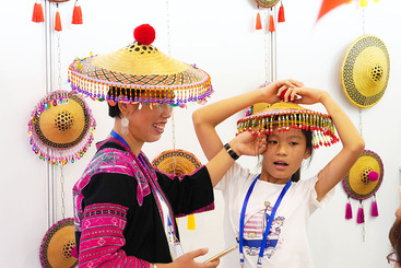 2019年8月30日，在南宁国际会展中心举行的2019广西工艺美术作品旅游工艺品暨大师精品展览上，人们在体验环江毛南族传统花竹帽。