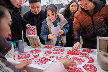 Z17443-9-277263-153****4267-中国剪纸在乡村（组照-8） 在当地组织的送文化下基层活动中，工地员工和附近村民在选取自己喜爱的窗花剪纸。2024年1月摄于四川雅安市318国道改线工地。