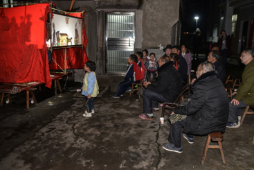 2019年4月4日晚，湖南平江县乡村正在演唱皮影戏，一小孩站在最前面观看。。
