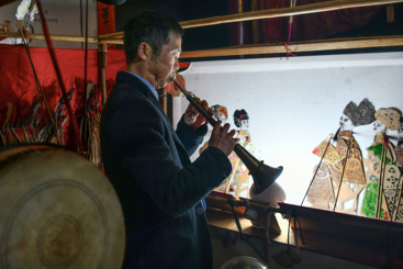 2023年4月8日晚，湖南平江县乡村正在演唱皮影戏，皮影艺人吹锁钠伴奏。