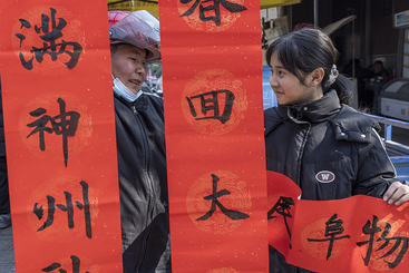 Z38227-2-277263-139****0426-3   2025.1.19  荆州市弥市镇街头 这位少年书法班的小美女拿着自己书写的联很自豪的告诉奶奶，这我写的。.jpg