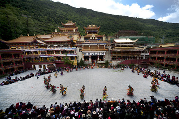 康定南无寺，“四月八”盛会，   跳神仪式开始，寺内鼓号齐鸣，喇嘛身着盛装，点燃松烟，一支由长柄鼓、铙钹、唢呐、莽号组成的寺庙乐队自大殿鱼贯而出，步下台阶，顺时针绕场一周坐定